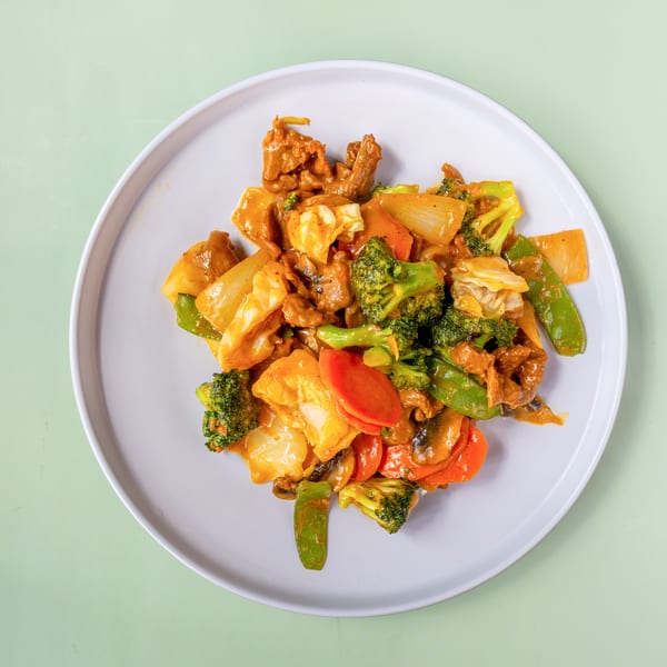 Beef and mixed vegetables stir-fry with broccoli, carrots, and snow peas on a white plate.