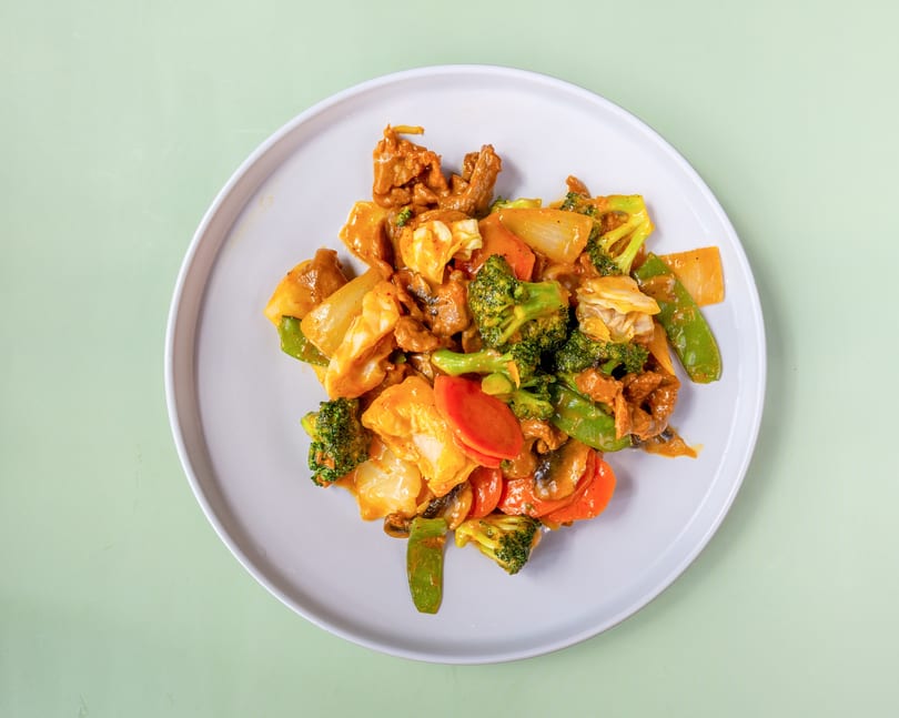 Beef and mixed vegetables stir-fry with broccoli, carrots, and snow peas on a white plate.