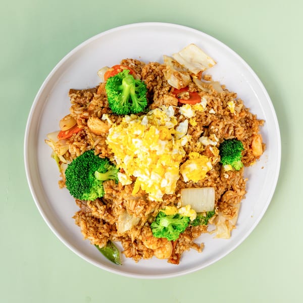 Fried rice with scrambled egg, broccoli, carrots, and shrimp on a white plate.