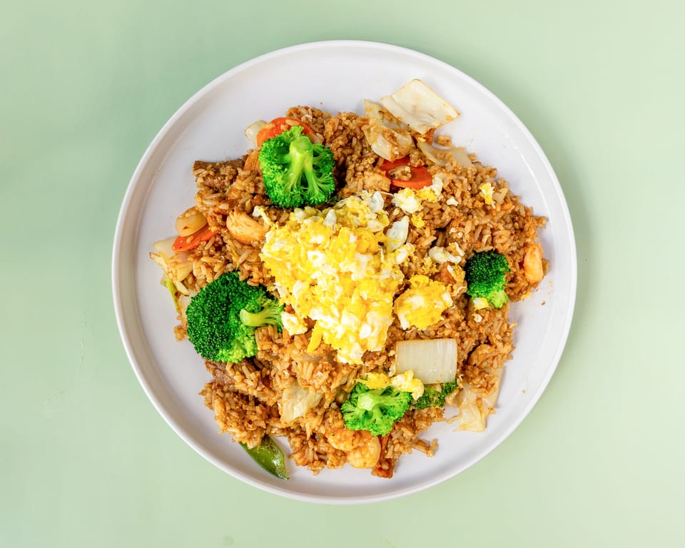 Fried rice with scrambled egg, broccoli, carrots, and shrimp on a white plate.